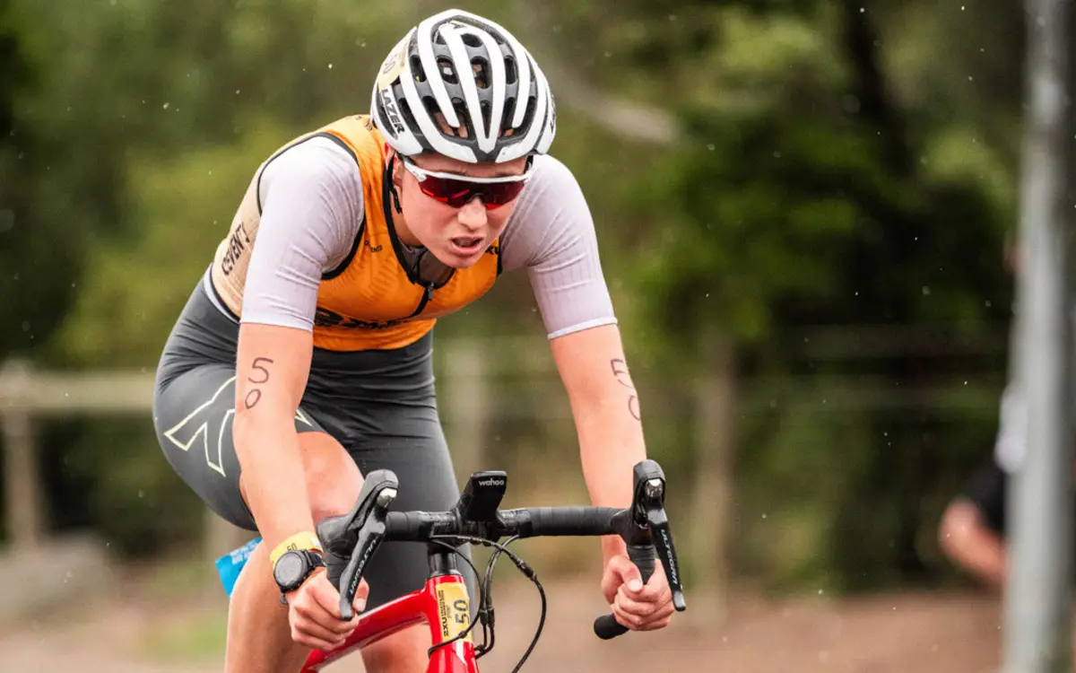 A competitor cycling along a tree lined road at a 2XU Tri-Series race.