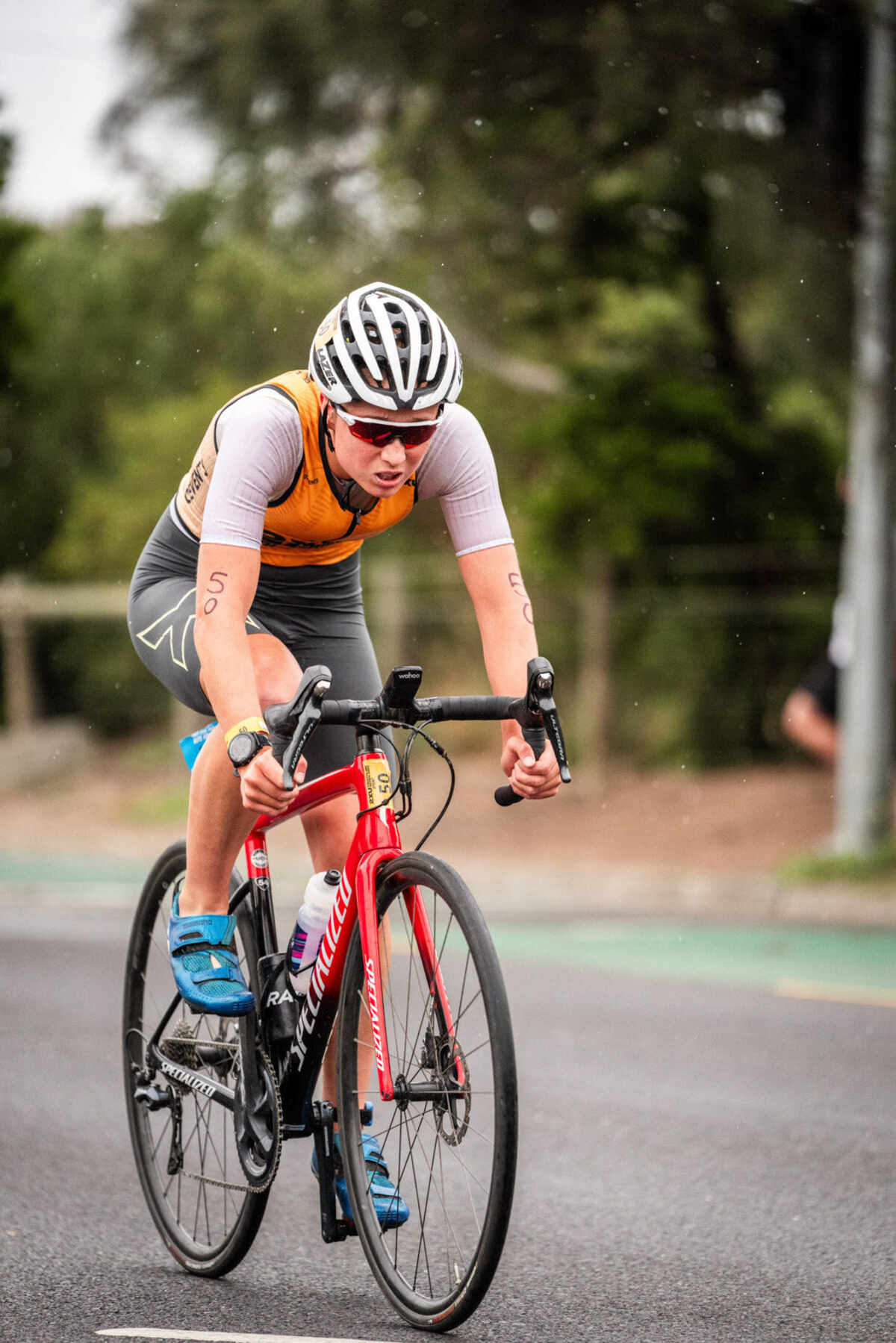 A competitor cycling along a tree lined road at a 2XU Tri-Series race.